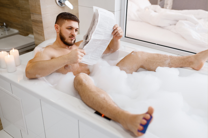 Man reading new paper while taking bubble bath