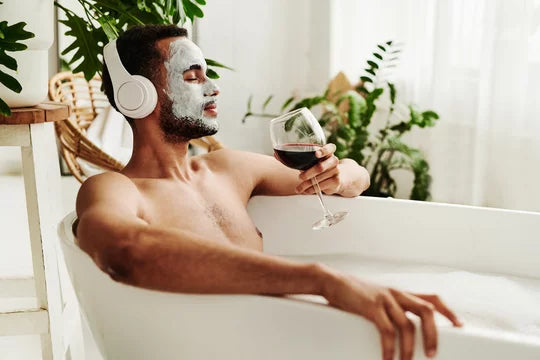 Man drinking wine in tub.